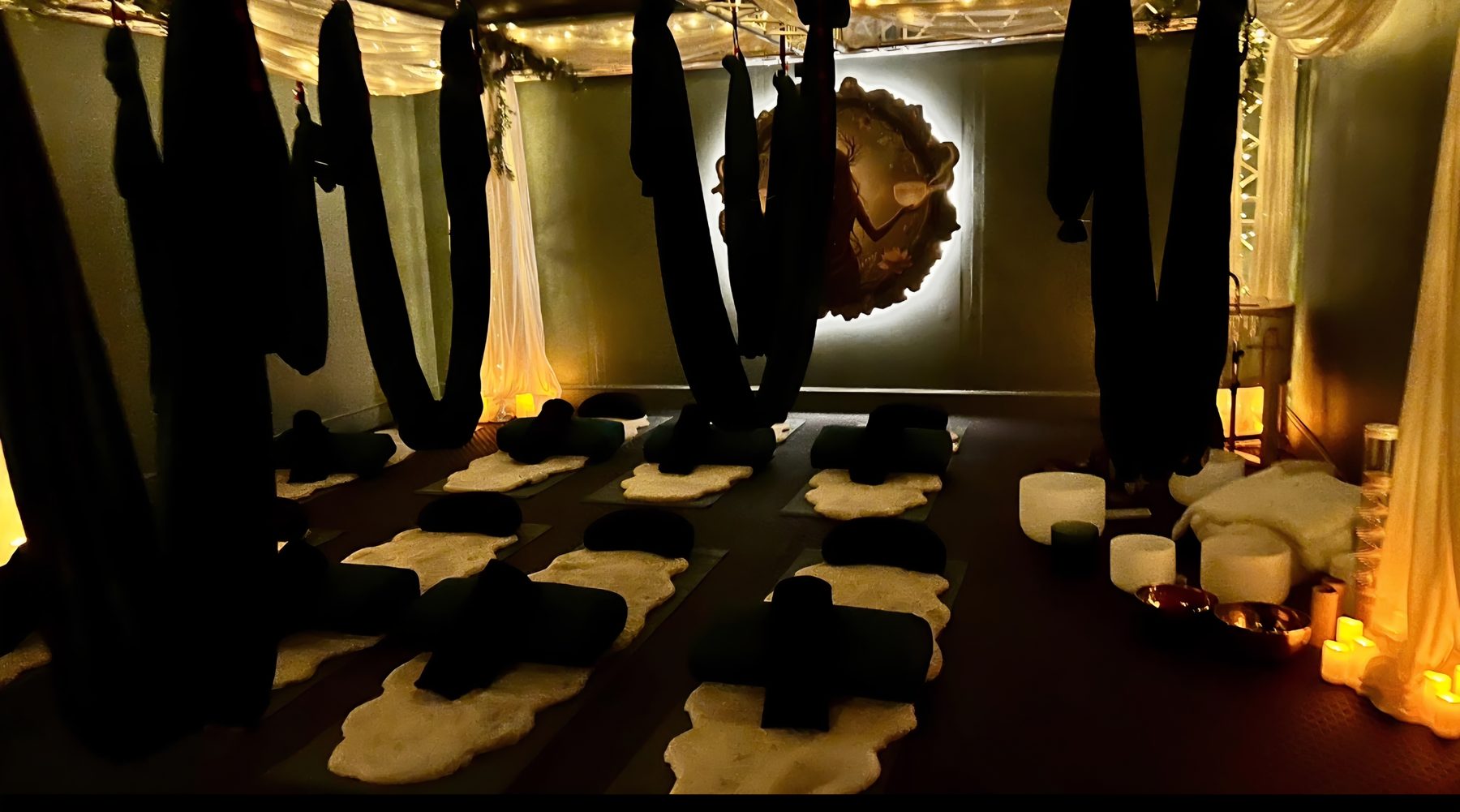 Candlelit meditation and sound bath space at Regulate Studio, with aerial hammocks, floor cushions and crystal singing bowls